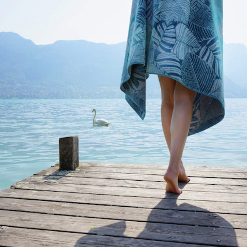 Anne de Solene Evasion Beach Towel - Woman walking with towel.