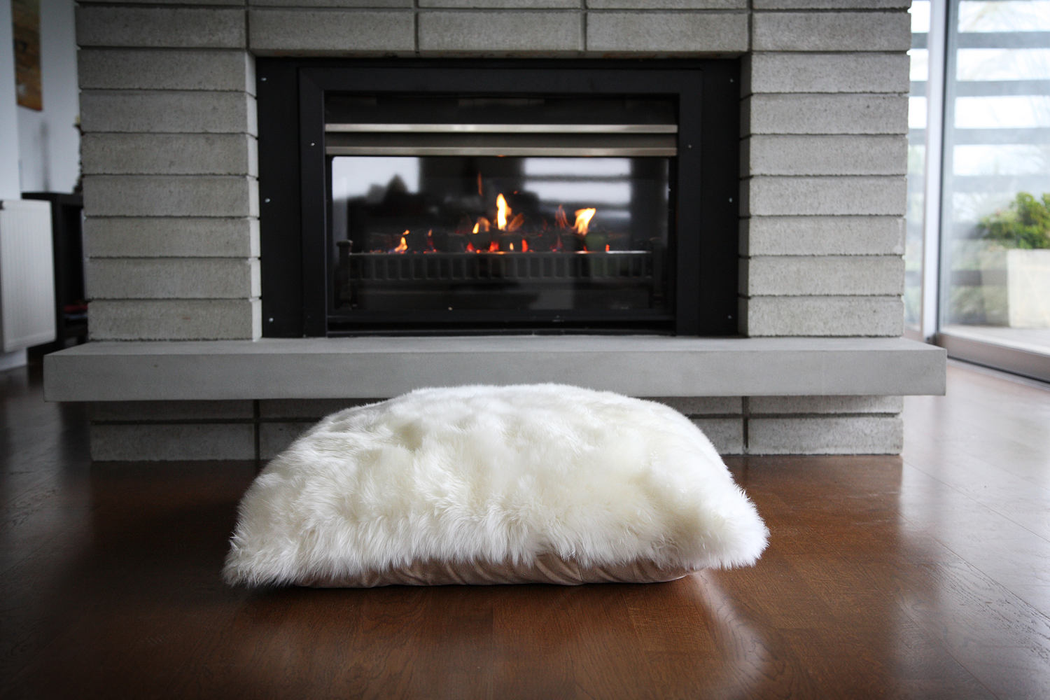 Fibre by Auskin Sheepskin Floor Cushion in front of fireplace